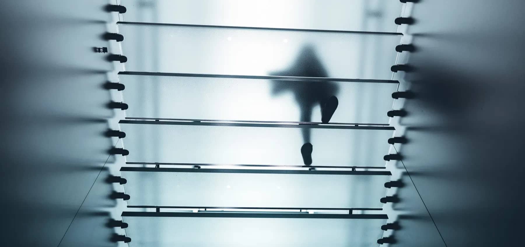 Emotional intelligence in succession, a figure crossing metal rails in soft focus.