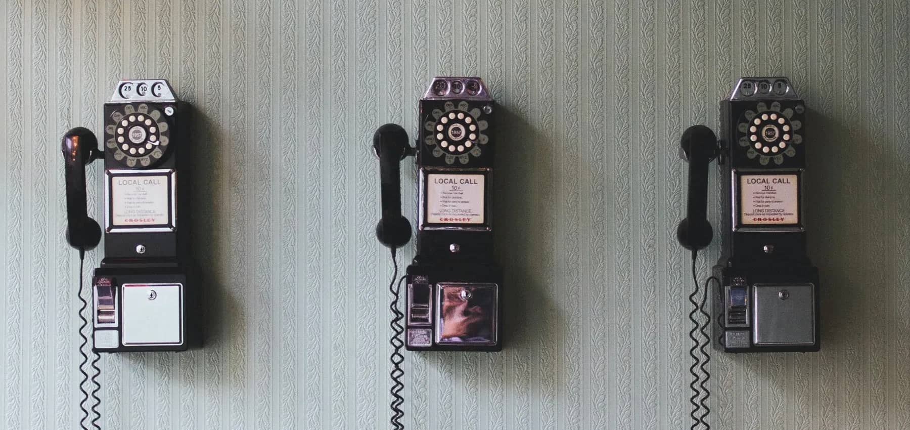 Australian family office technology, three vintage payphones mounted in a row on a wall.