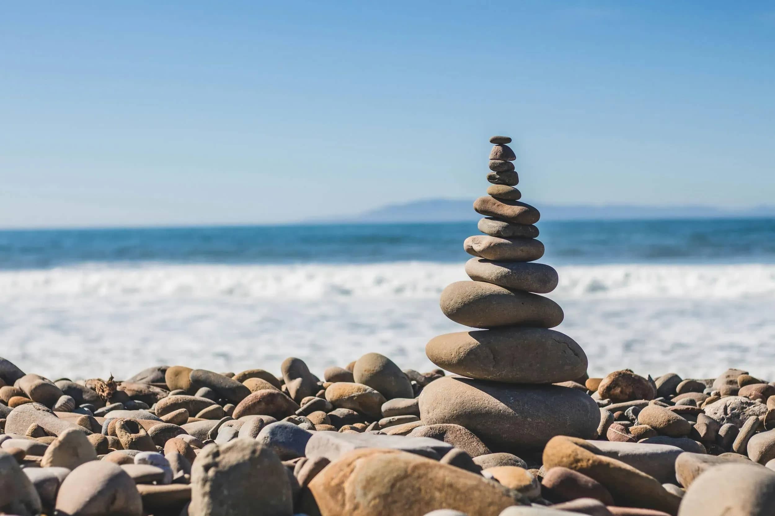 Concierge healthcare, a stack of balanced stones on a beach before the sea.