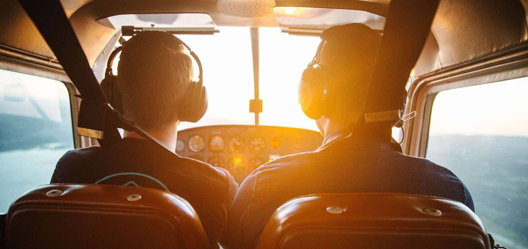 Family governance principles, two pilots seen from behind in a cockpit at sunrise.