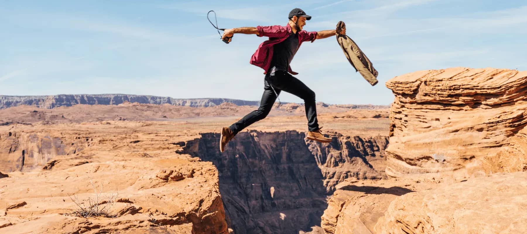 Engaging the next generation, a person leaping across a gap between two canyon ledges.