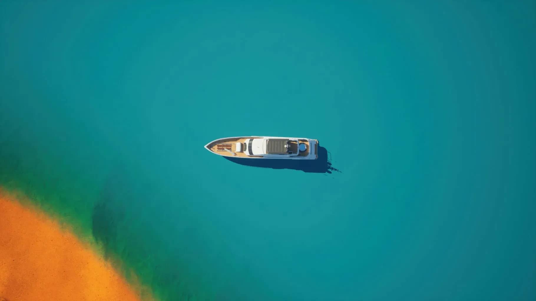 The UHNWI of today, a boat seen from directly above on clear turquoise water.