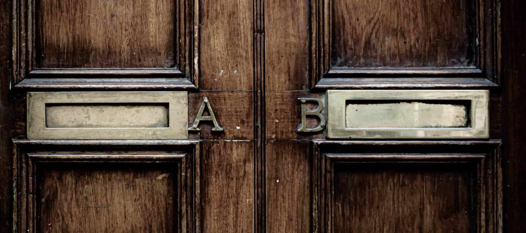 Family office alternative investments, two ornate wooden doors side by side, their brass letter plates marked A and B.