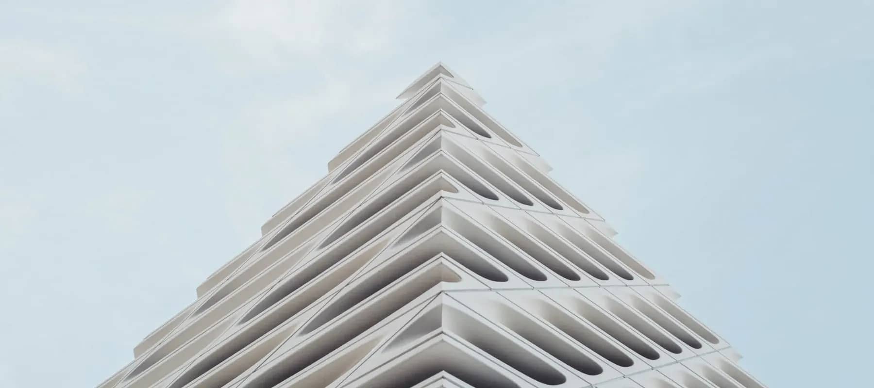 Alternative investments, a stepped white concrete building rising against a pale sky.