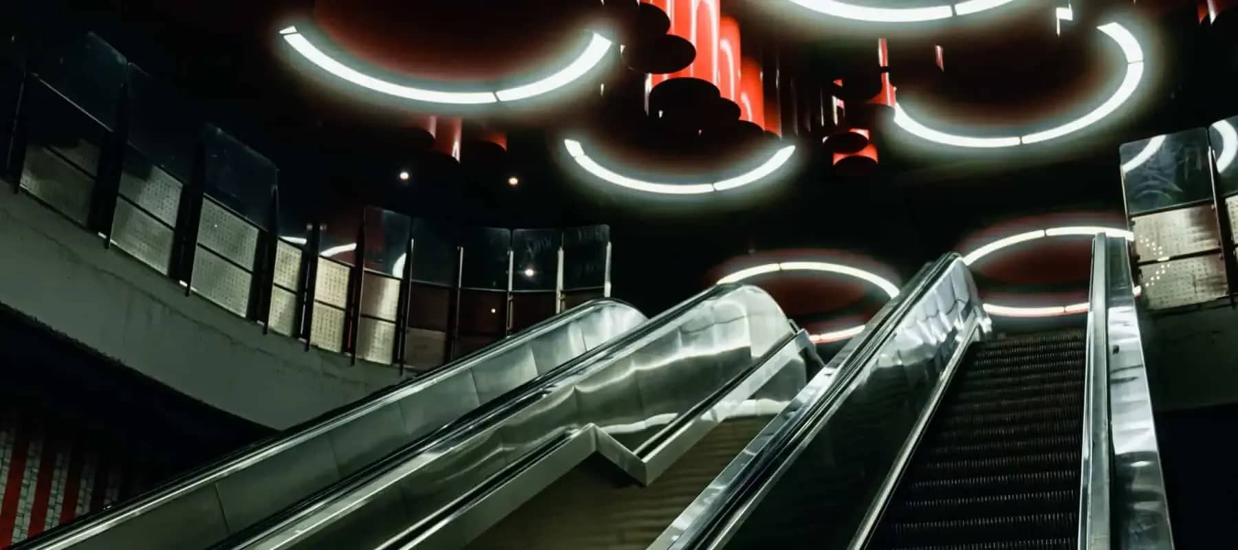 Family office bill pay, escalators descending beneath circular ceiling lights.