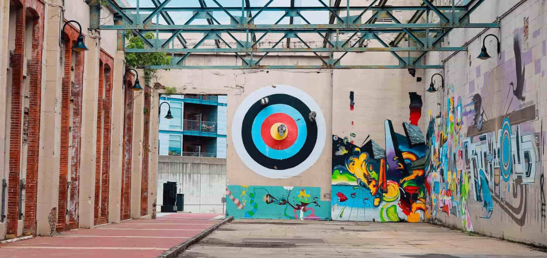 Activist philanthropy, an archery target painted on a brick wall beside graffiti.