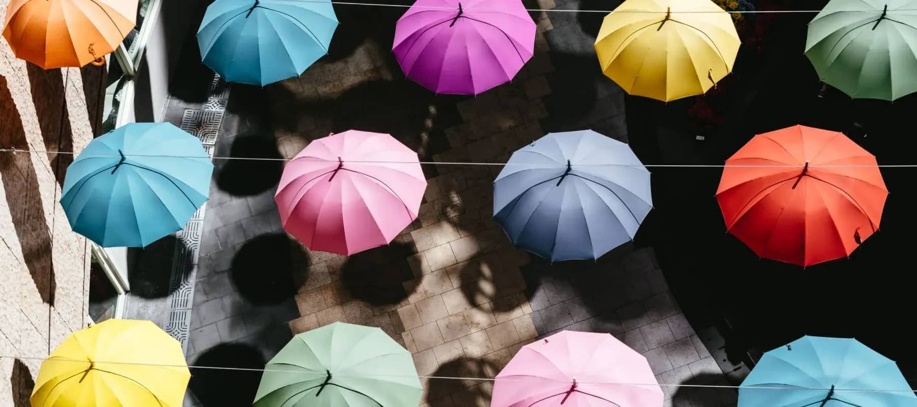 Accounting across multiple entities, four coloured umbrellas hanging on a line seen from above.