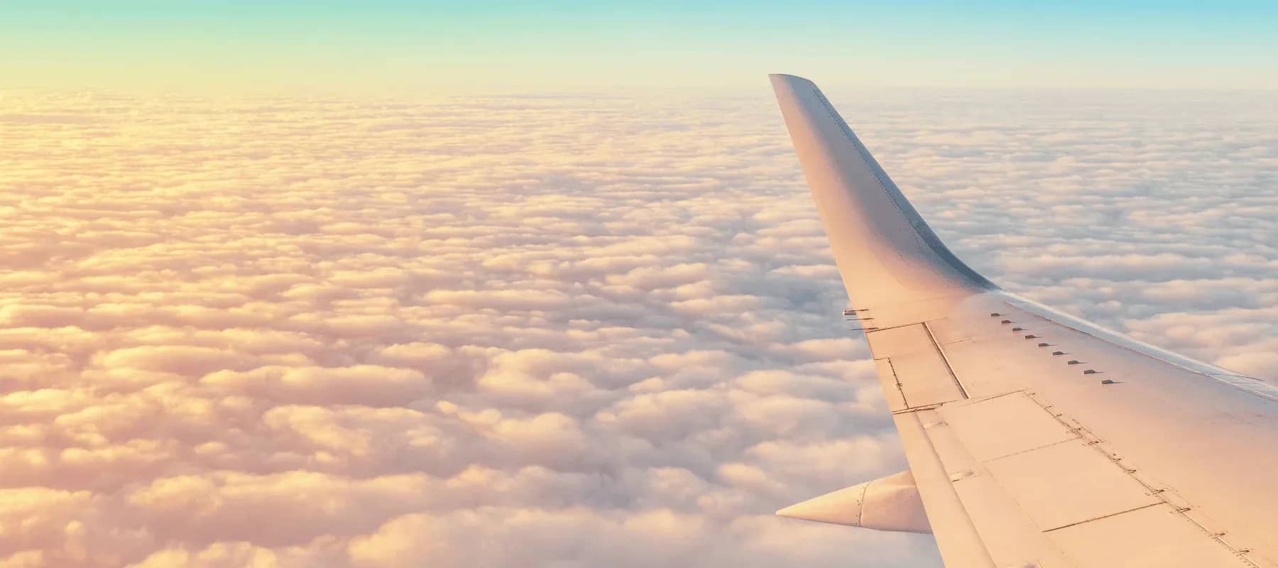 Concierge services beyond the itinerary, an aircraft wing above a sea of golden cloud.
