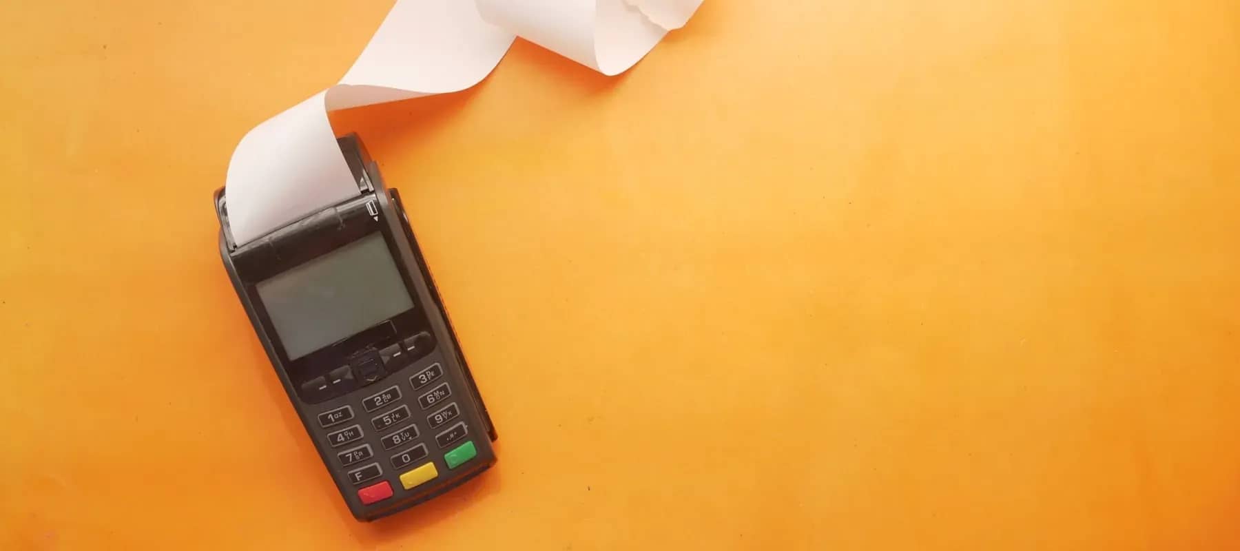 Family office costs, a card payment terminal printing a receipt on a bright orange surface.
