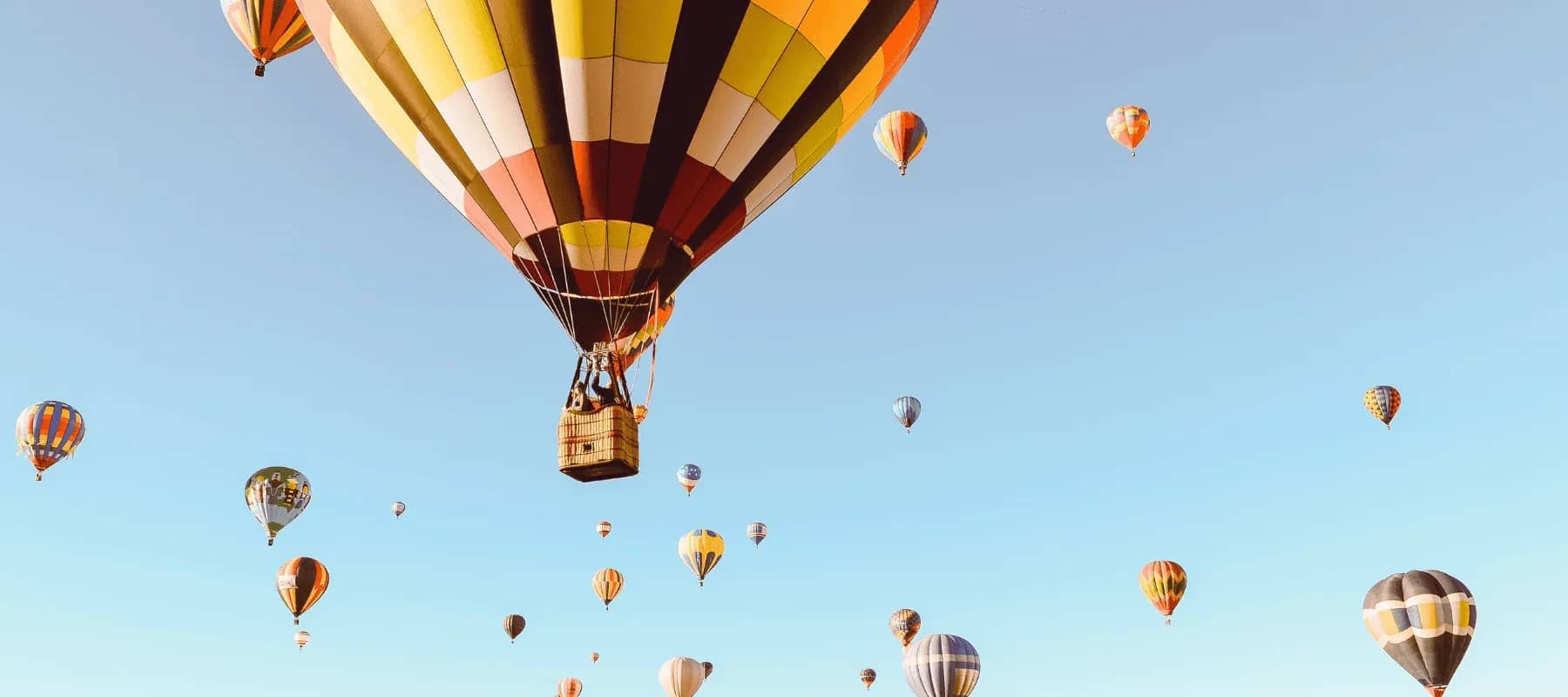 Global health insurance, hot air balloons drifting across a pale blue sky.