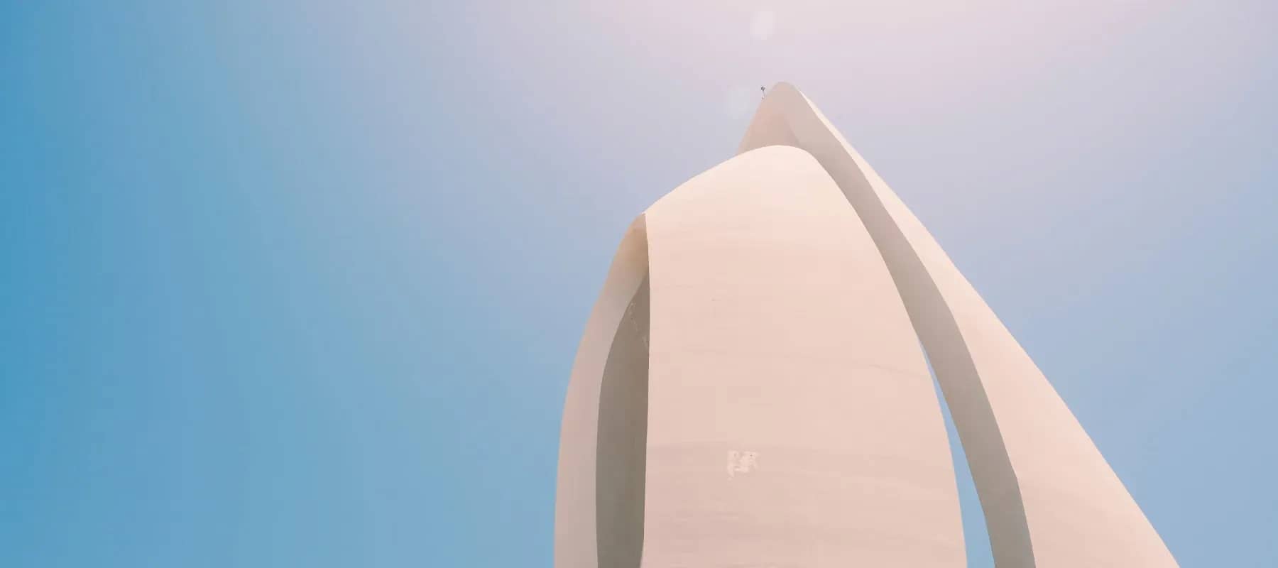 Family office privacy and publicity, a smooth curved pale sculpture against a blue sky.