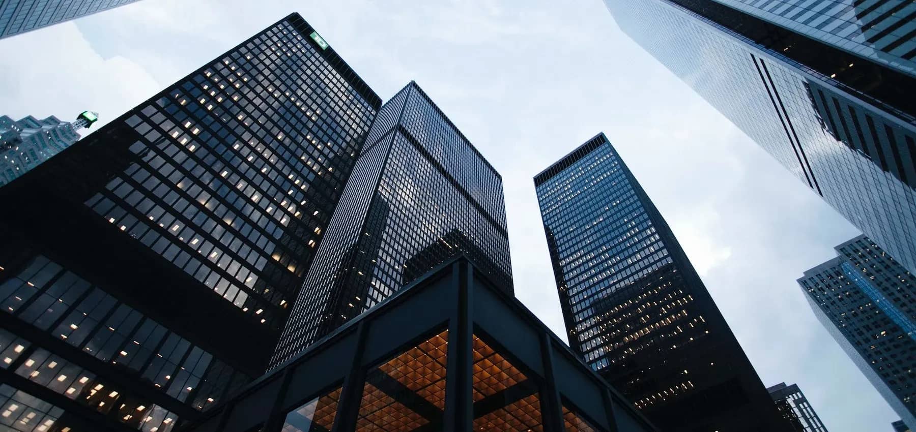 Family office operating model, glass office towers seen from street level against an open sky.