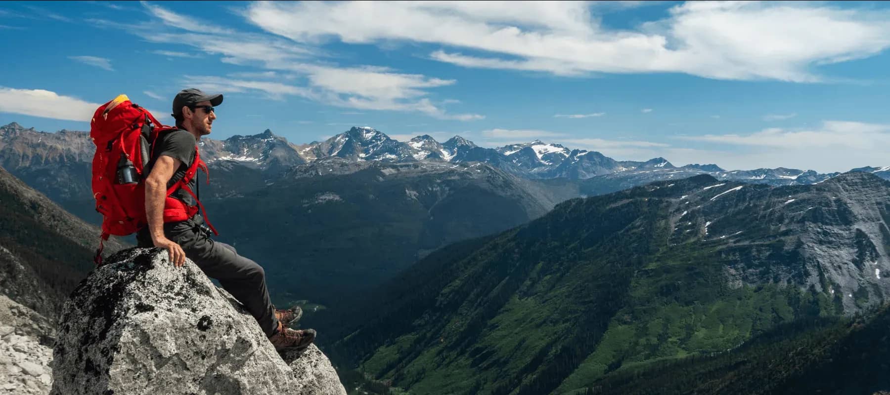 From founder to family office, a hiker with a red pack looking out over a mountain range.