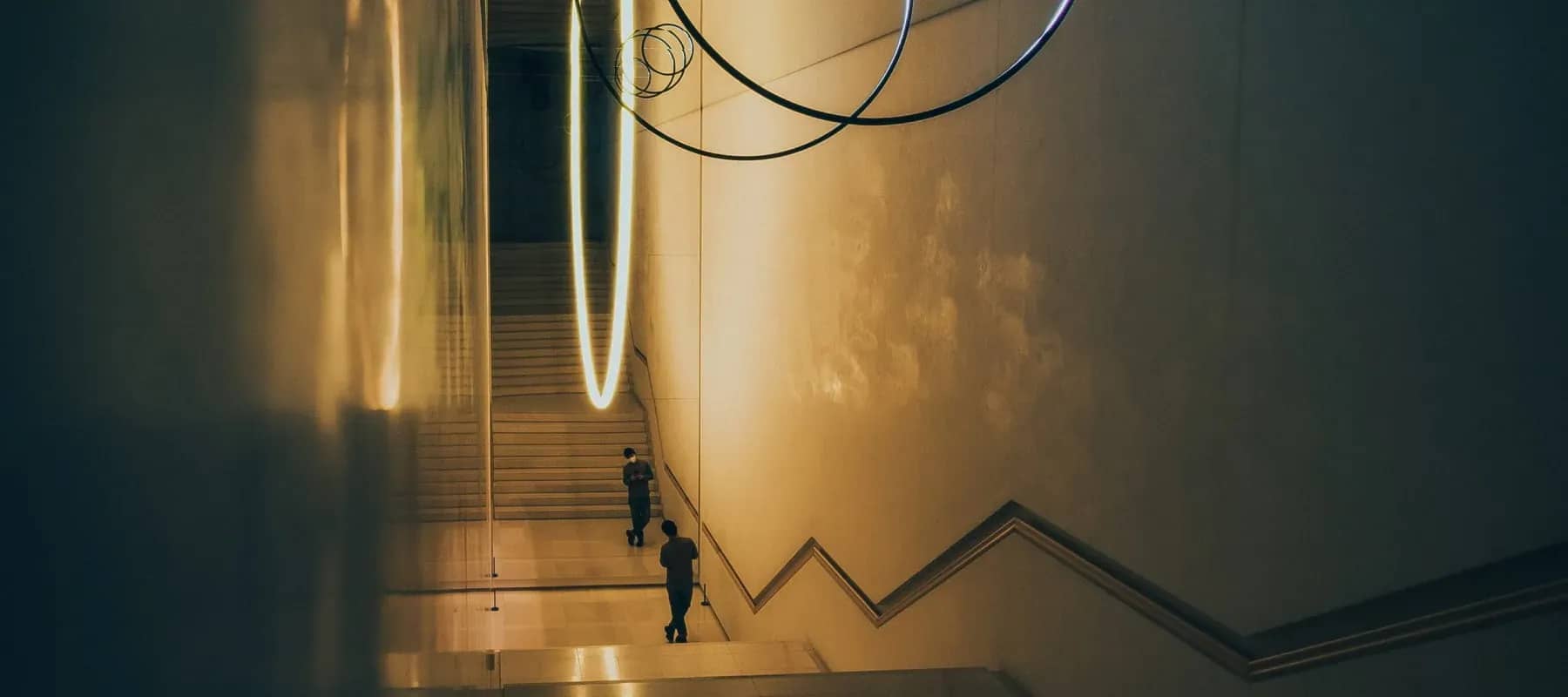 From possessions to experiences, a grand staircase lit in warm gold with a lone figure below.