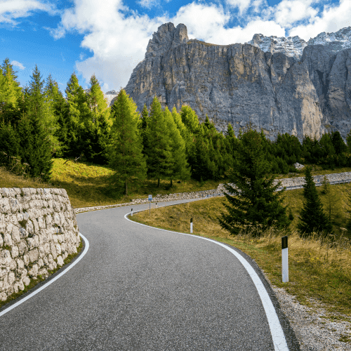 Mountain road winding through a forest towards high cliffs, symbolising a clear path to unified multi-asset management and reporting for family offices with FundCount.