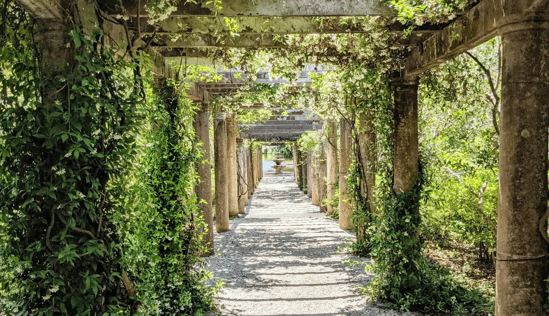 Consolidated view of all assets, a stone pergola walkway draped in greenery leading to a distant fountain.