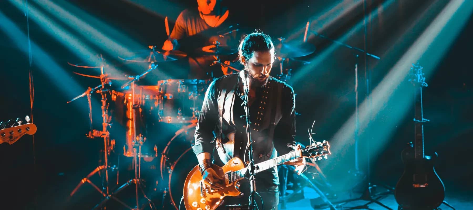 Family offices serving musicians, a guitarist performing under blue stage lights.
