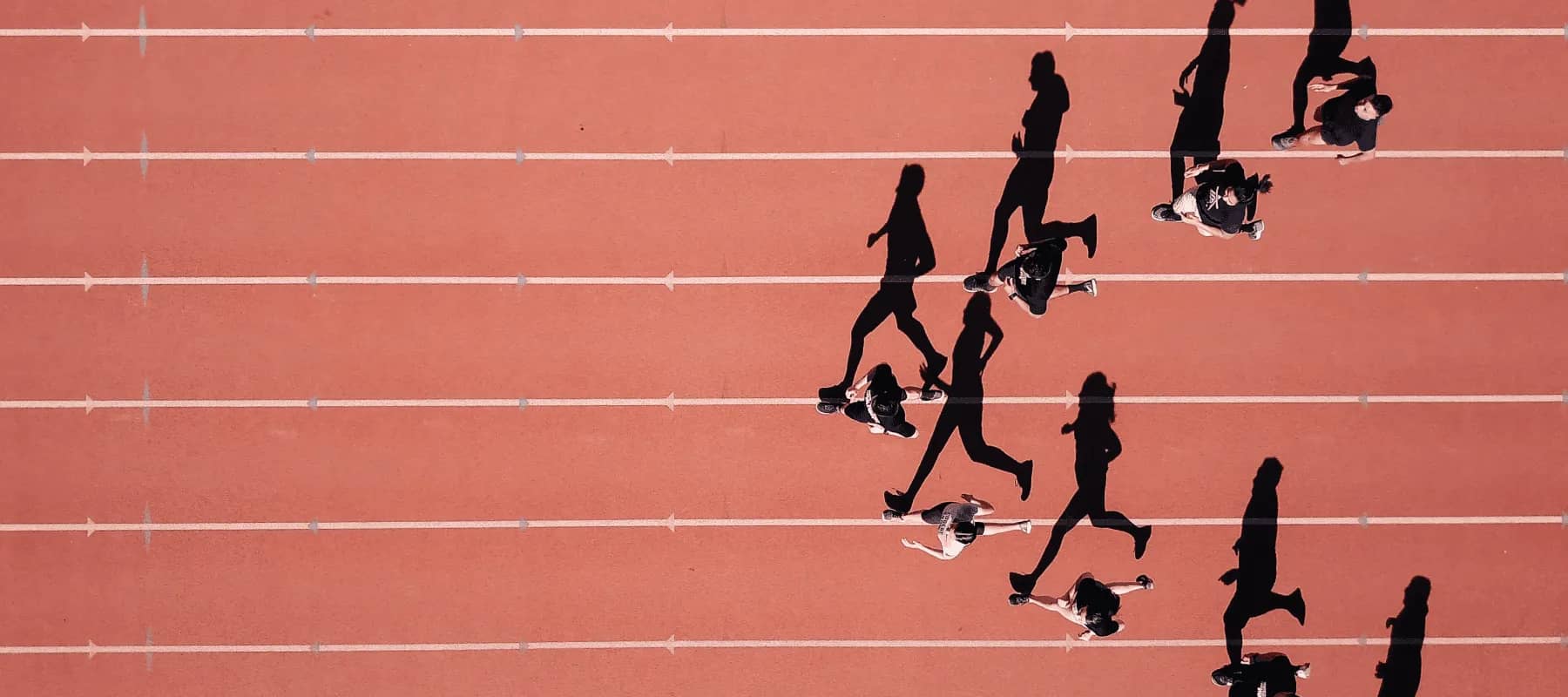RIAs and family office services, runners spread across a red athletics track seen from above.