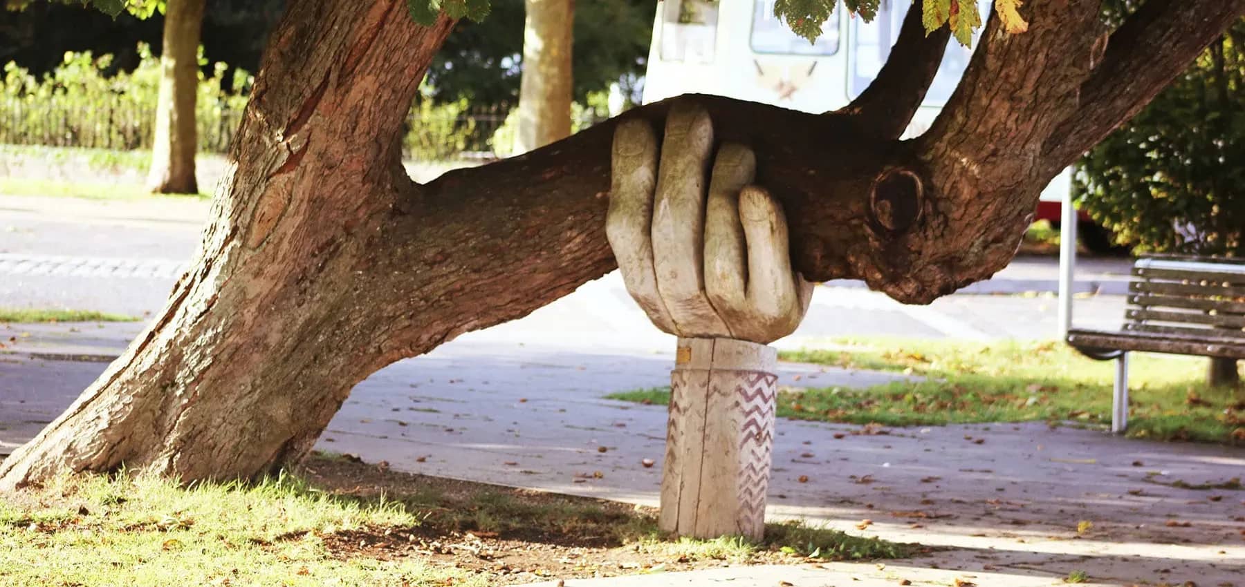 Matriarchal and patriarchal roles, a carved wooden hand propping up a leaning tree branch.
