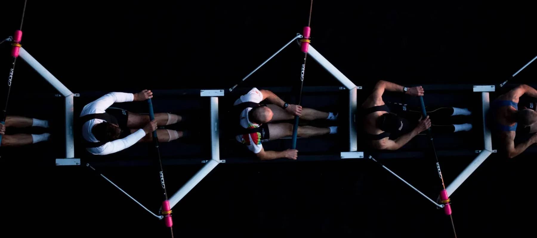 Family office outsourcing, rowers training in unison seen from above.
