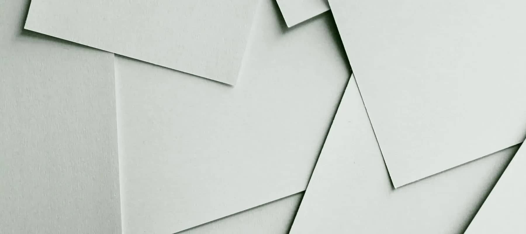 Family office portfolio management, overlapping sheets of pale paper layered at angles, casting soft shadows.