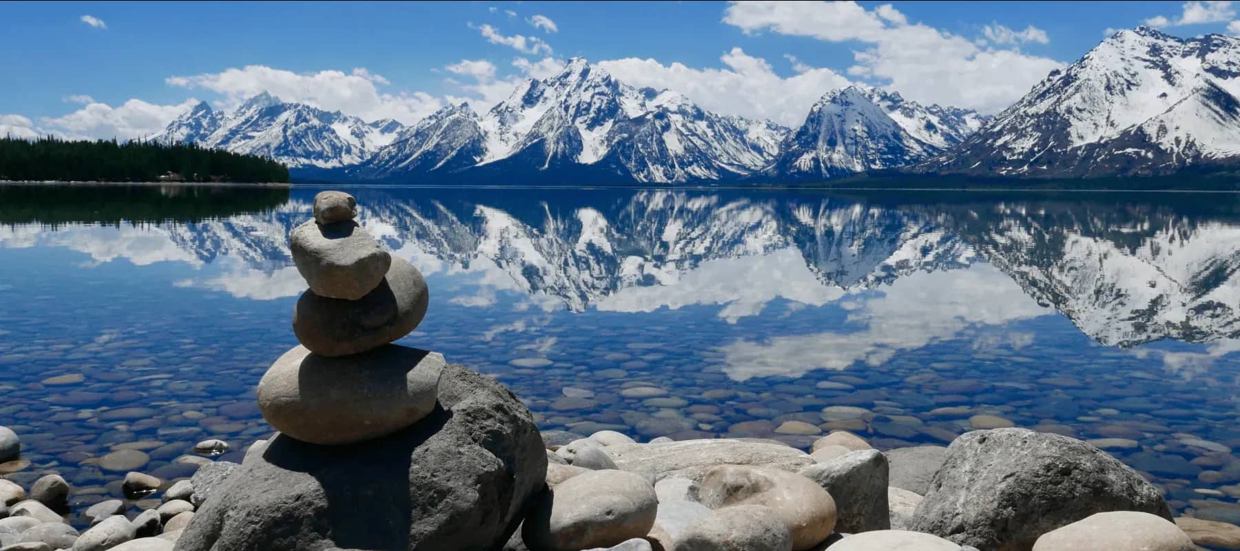 Private equity allocation, a cairn of balanced stones before a mountain lake.