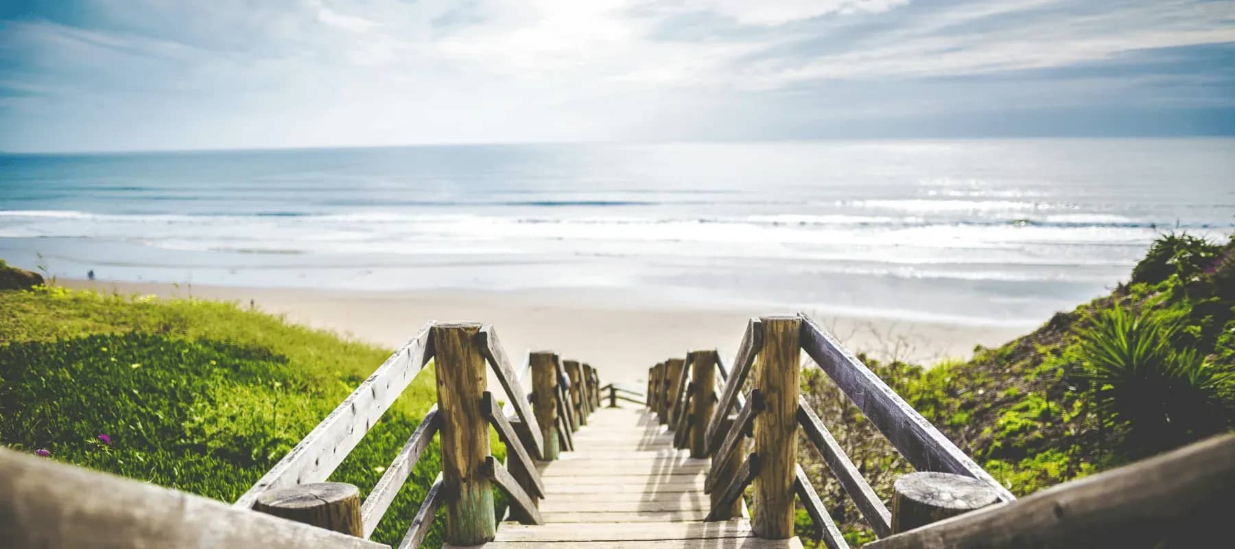 Concierge medicine for family offices, a wooden boardwalk leading down to a wide beach.