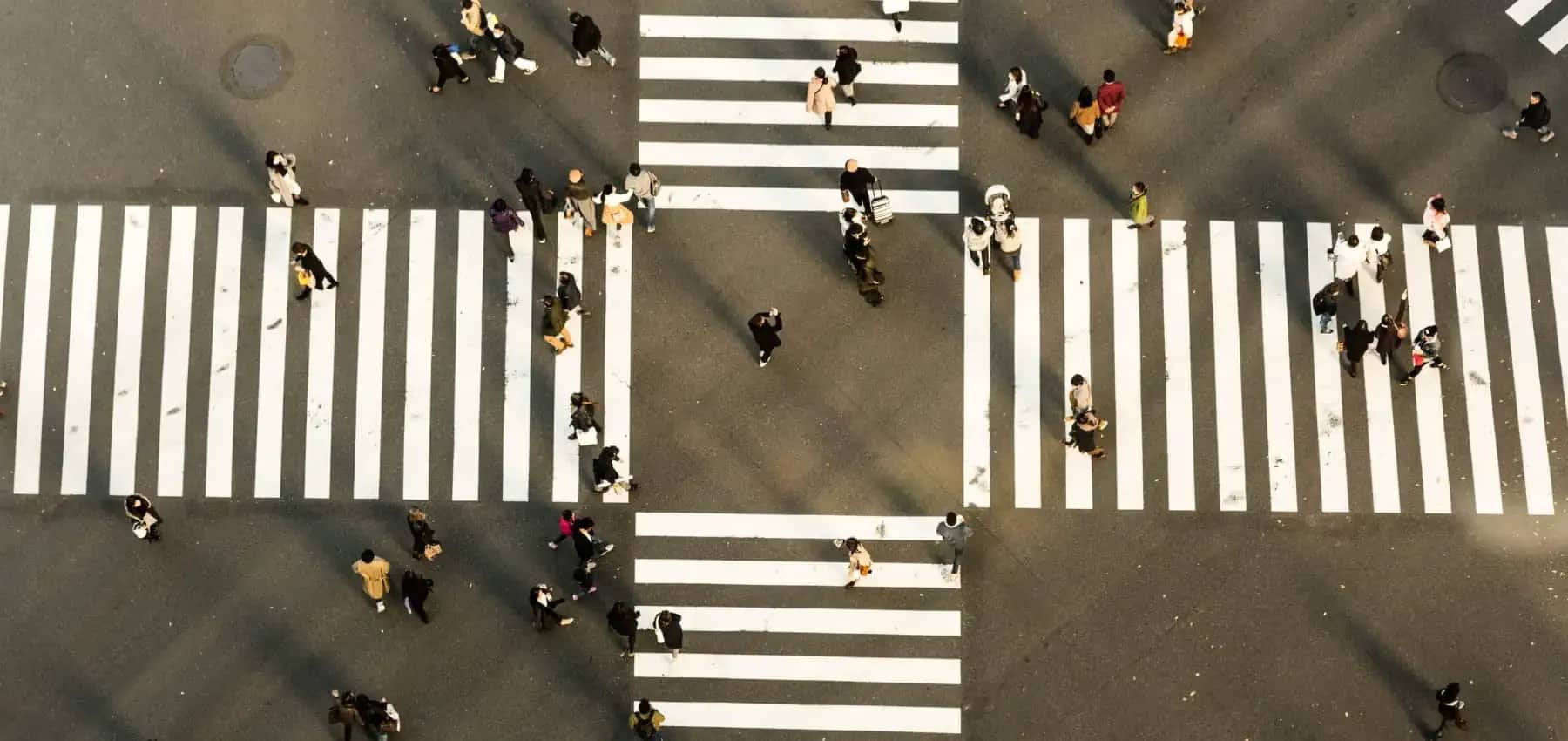 Real estate funds versus direct investment, pedestrians crossing striped walkways seen from above.