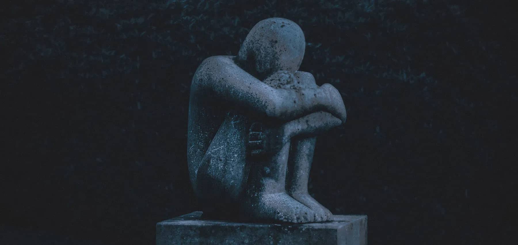 Family office succession after a death, a weathered stone figure seated in deep blue shadow.