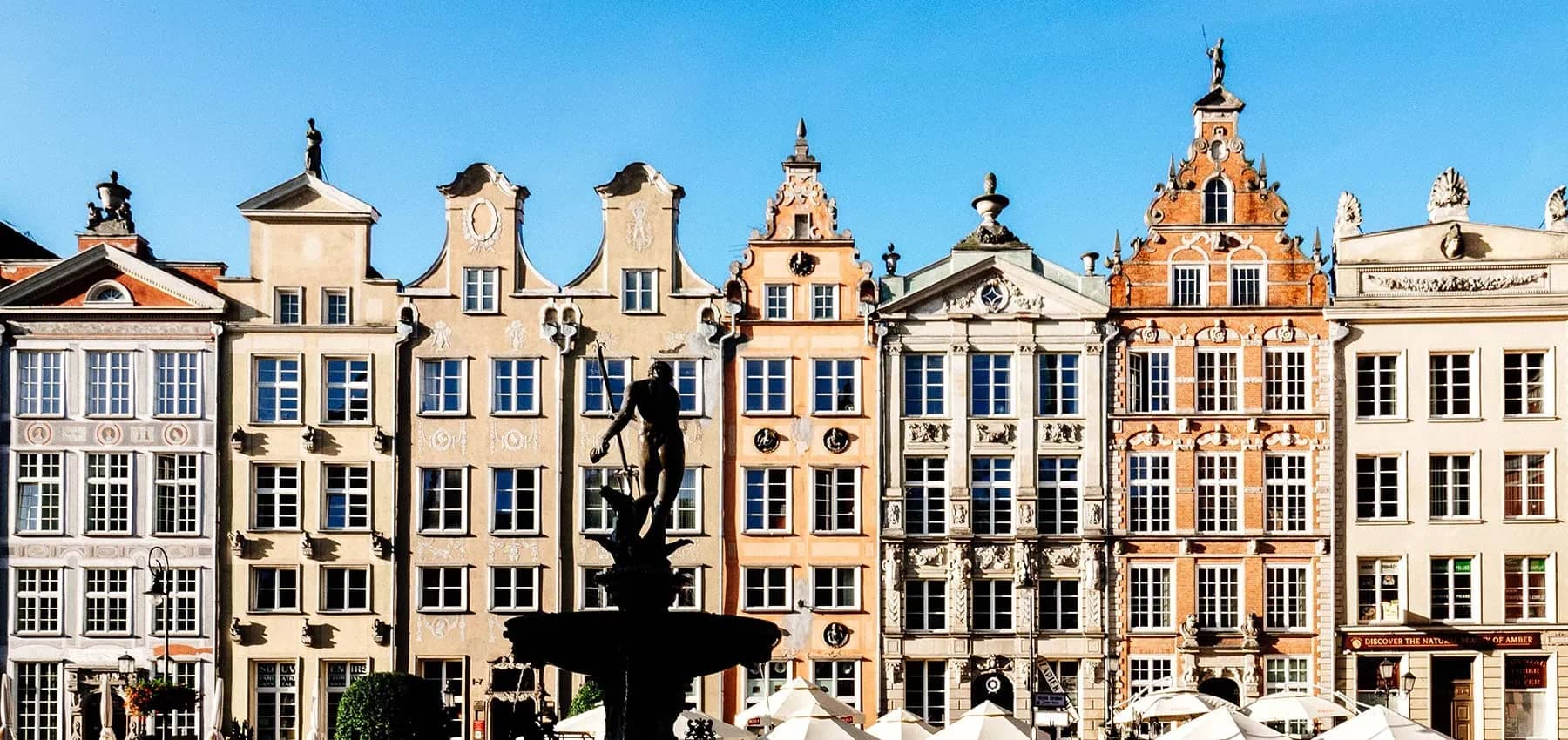 Eastern European markets, ornate Hanseatic townhouse facades with a statue in front.