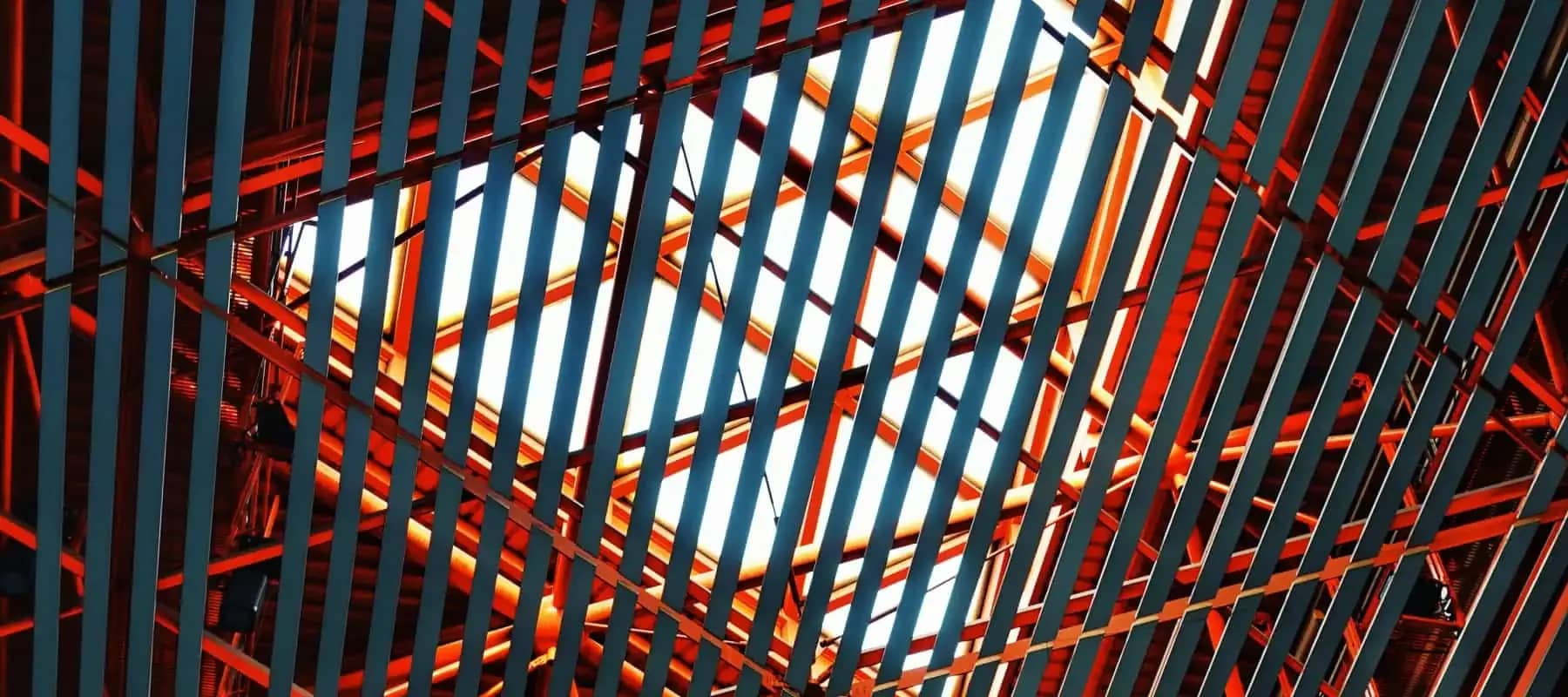 Venture capital and impact, red and blue structural steelwork crossing in the frame.