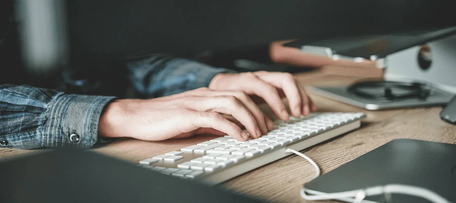 WealthTech innovation, hands typing at a keyboard on a wooden desk.