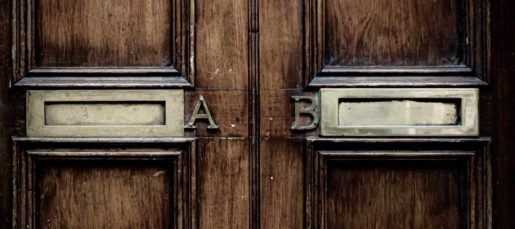 Family office alternative investments, two ornate wooden doors side by side, their brass letter plates marked A and B.