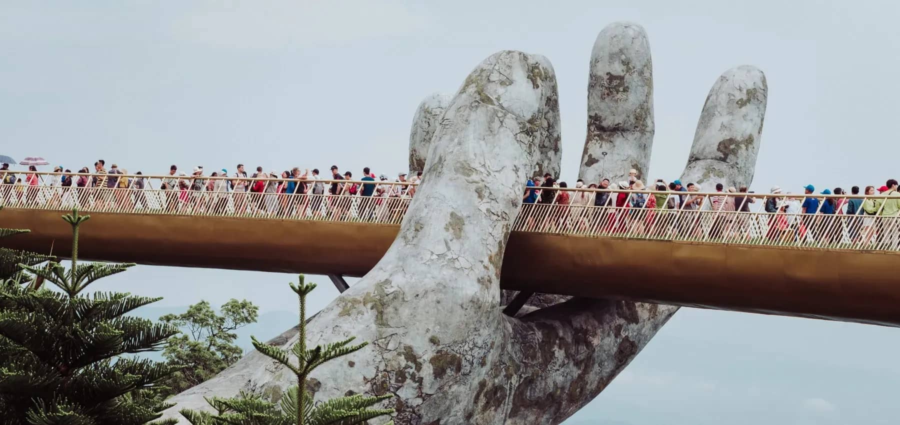 Family business brand frameworks, a curved footbridge held aloft by giant stone hands, crowded with visitors.