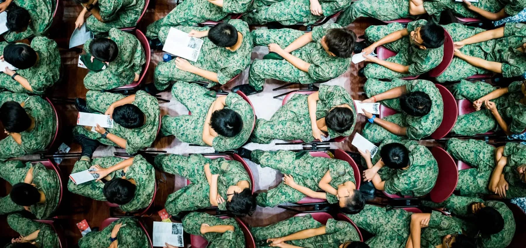 Asian family business, an overhead view of students in green uniform seated in rows, writing.