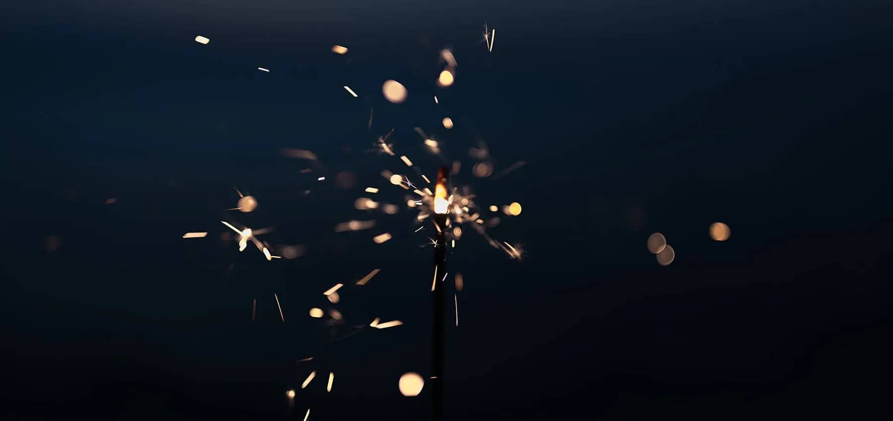 Swiss family offices, sparks scattering from a lit sparkler against darkness.
