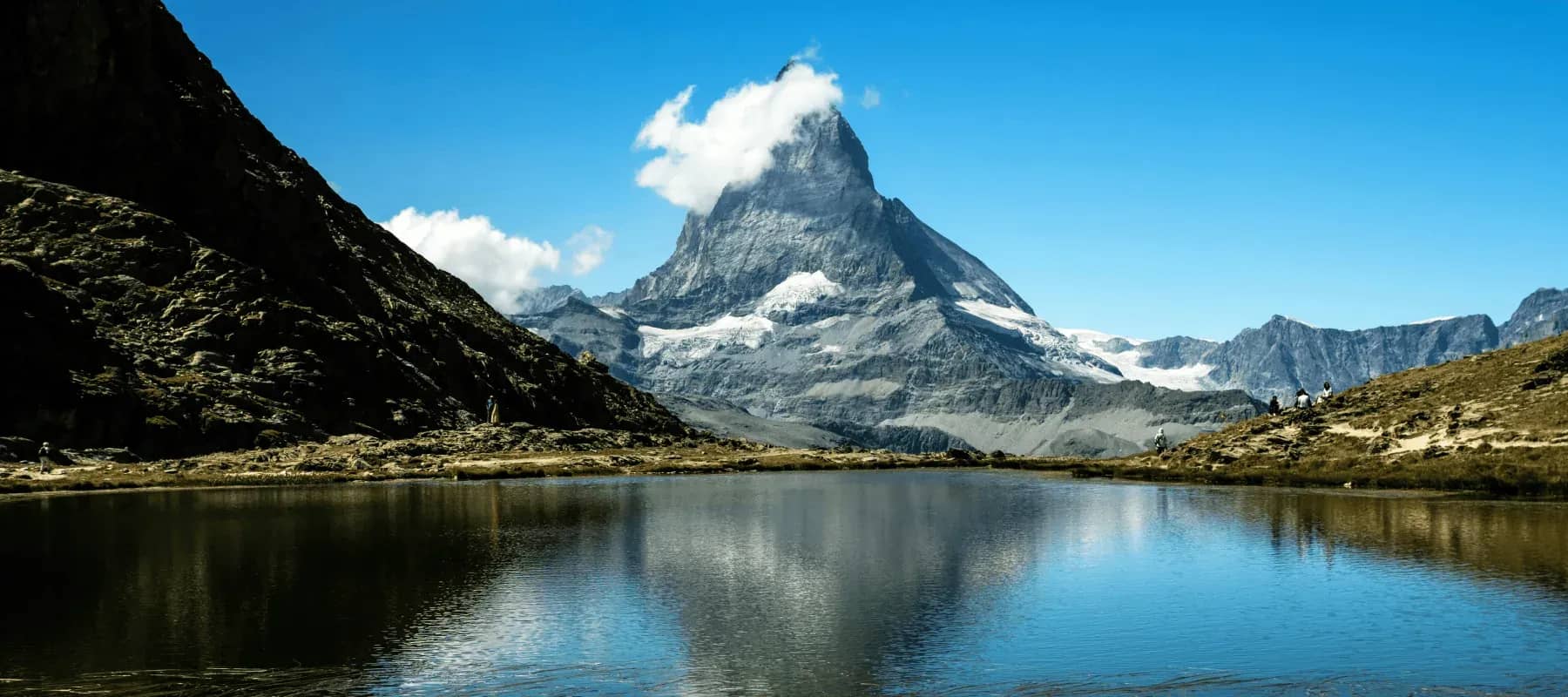 Modern wealth management, a snow-capped alpine peak above a still lake.