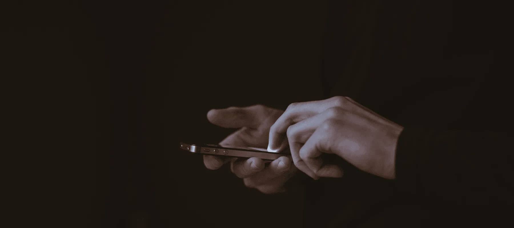 AI-powered accounting, a hand holding a phone lit in near darkness.