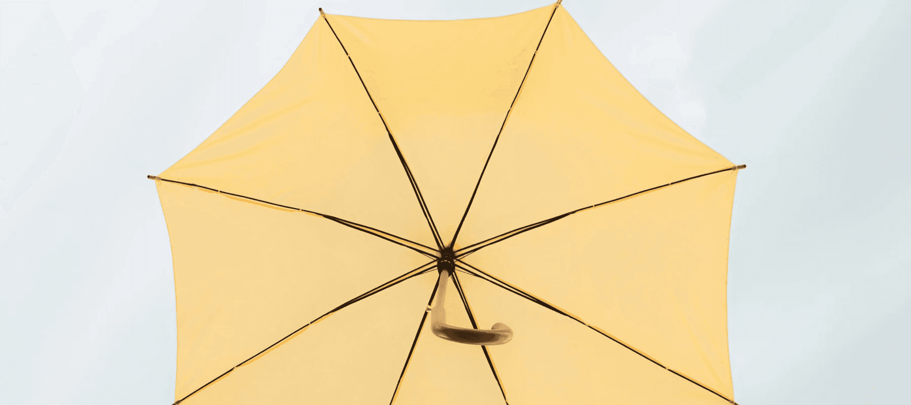 A low-angle view of a bright yellow umbrella against a pale sky, representing an integrated layer of AI for family office software.