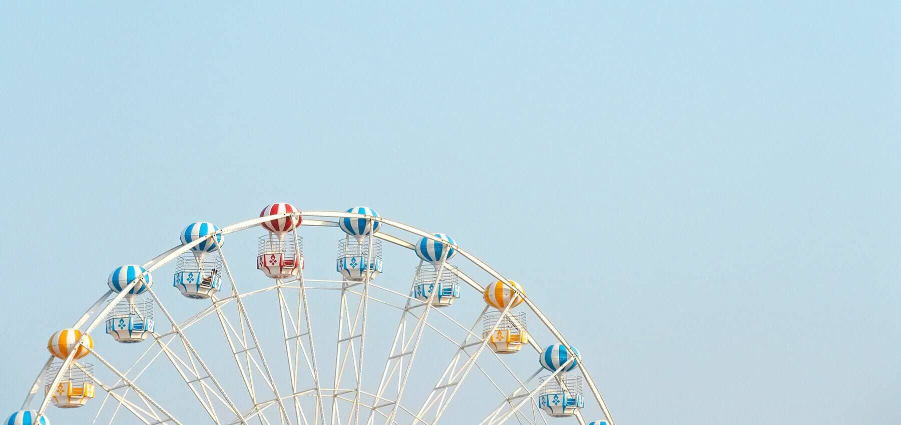 Cyclical business thinking, a ferris wheel against a pale blue sky.