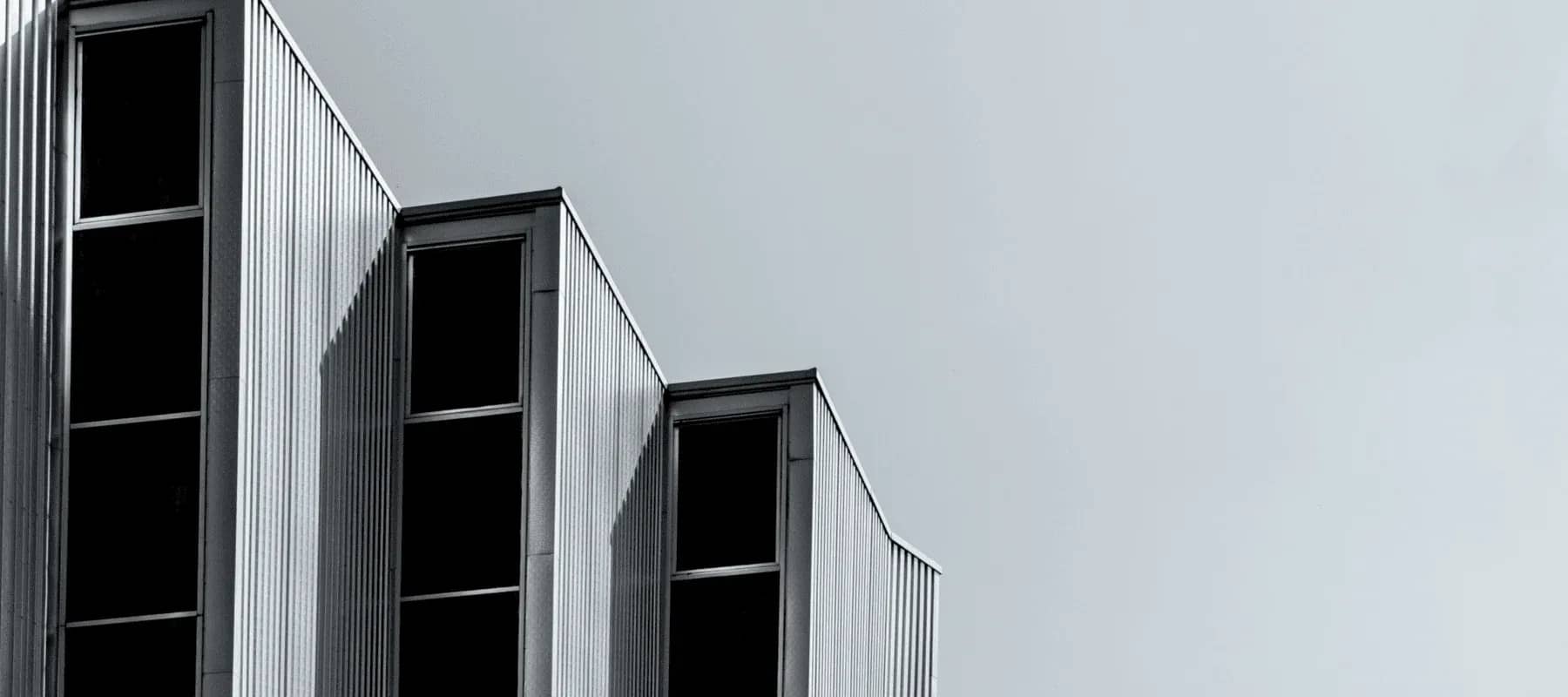 Family office reporting efficiency, a corrugated metal building facade in sharp monochrome.