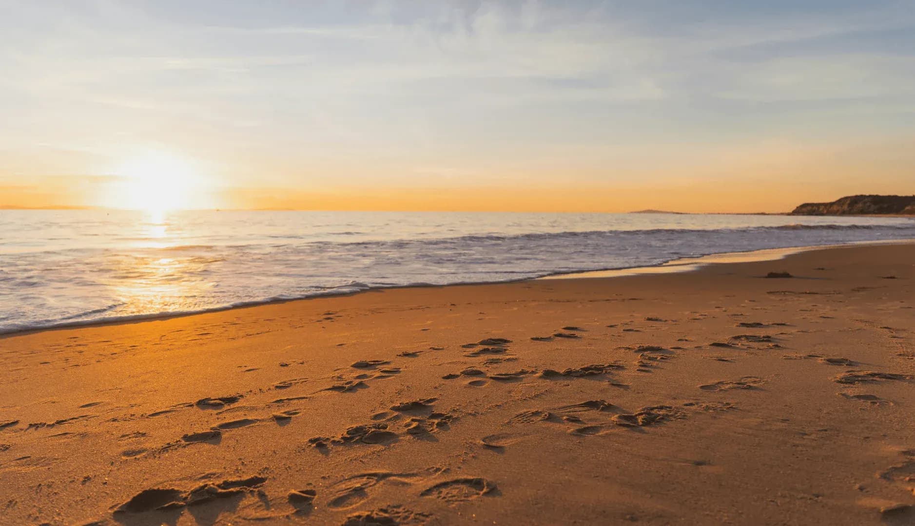 Family office cybersecurity, a wide empty beach at sunset with footprints leading along the shoreline.