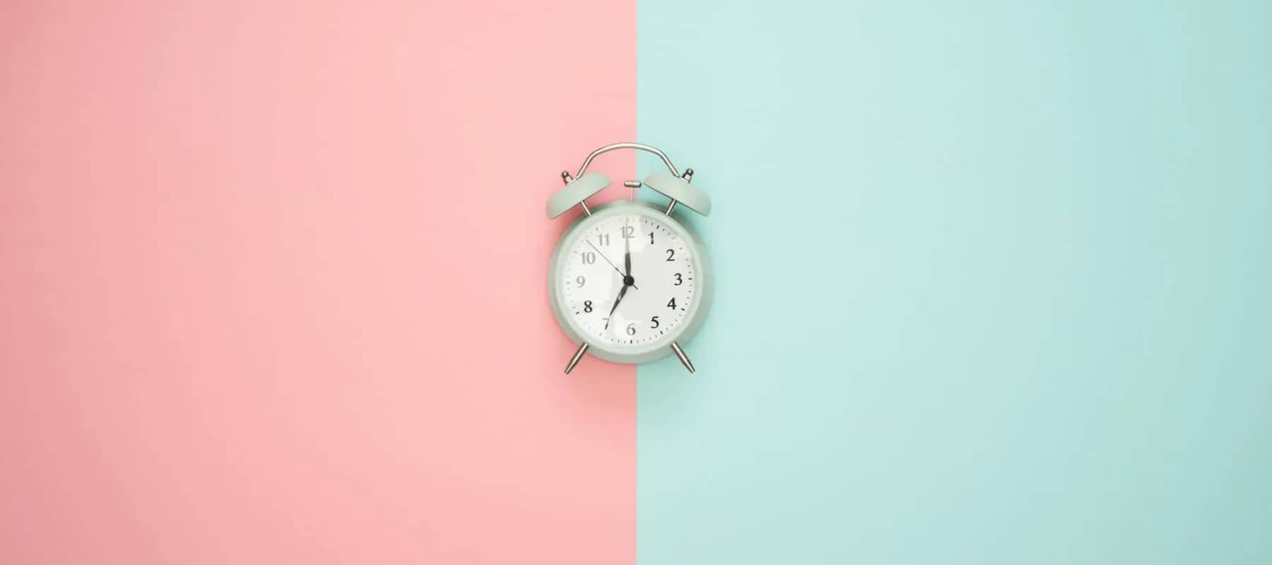 Family office technology adoption, a pale alarm clock against split pink and mint backgrounds.