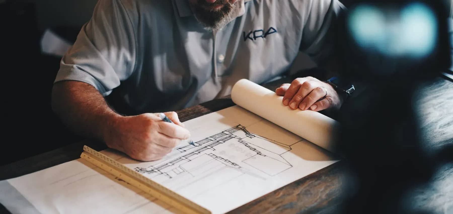 Family offices investing in real estate, hands drafting on architectural blueprints.