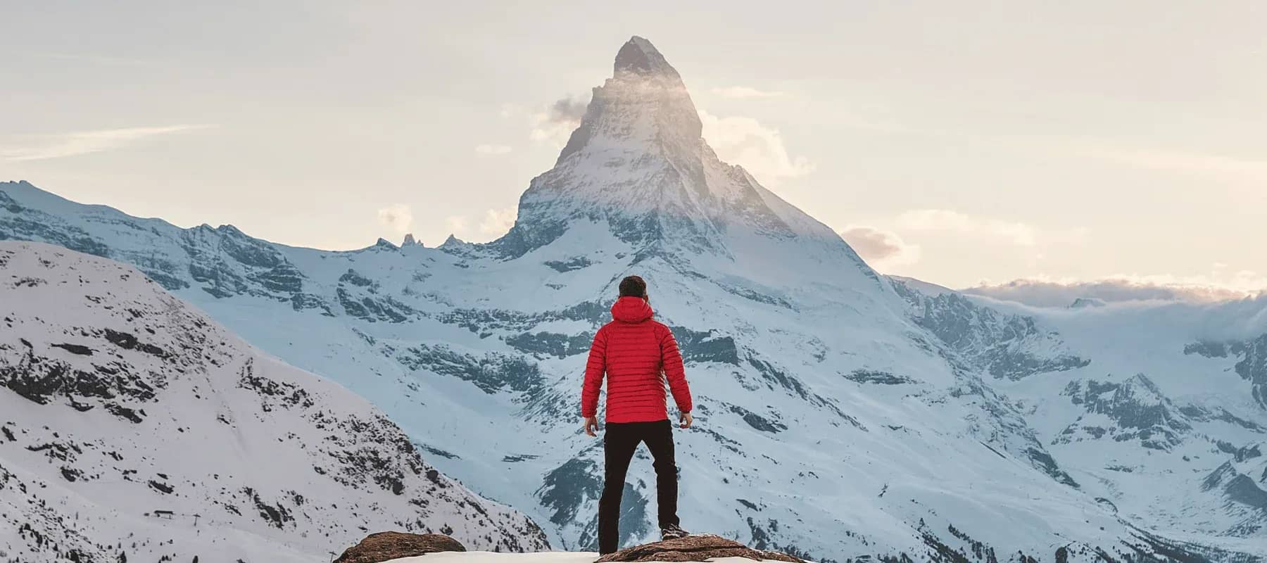 Generative AI for family offices, a figure in a red jacket facing a snow-covered peak.