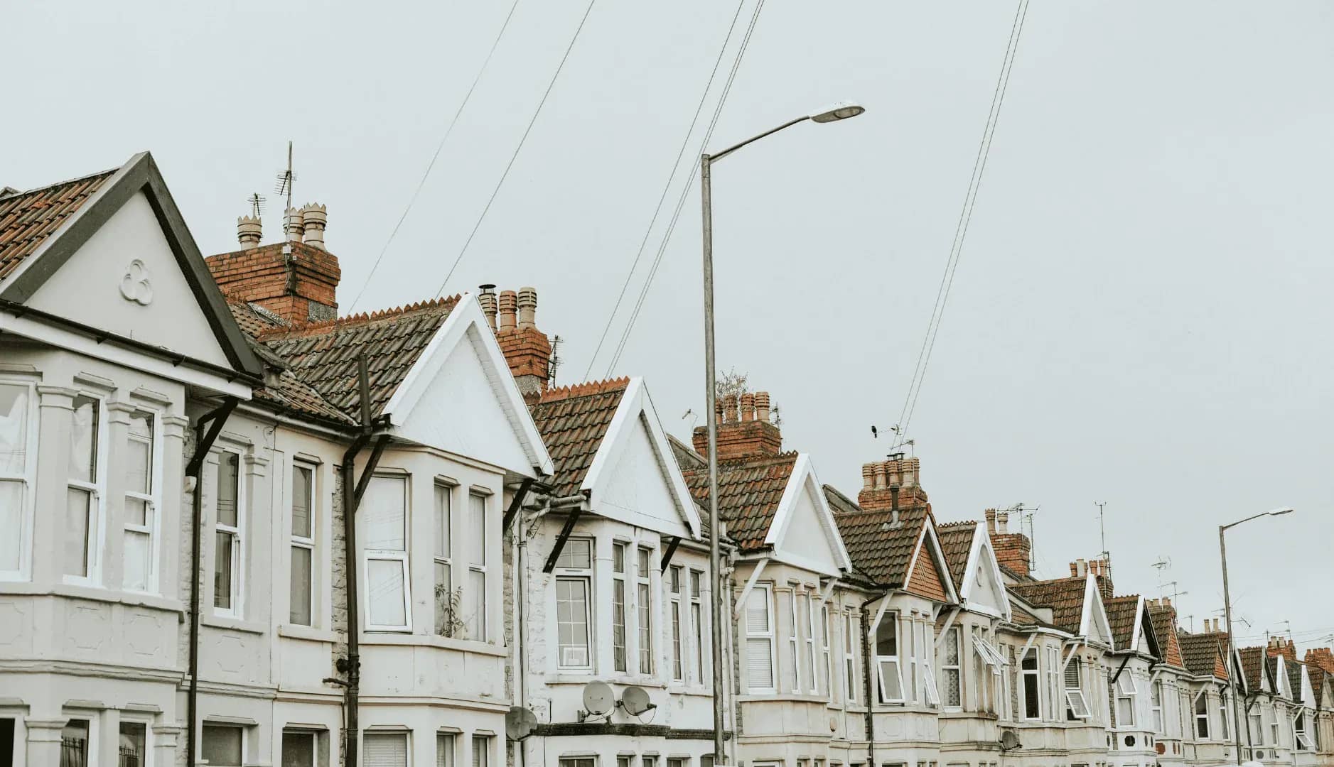 Family inheritance property portfolio, a row of gabled terraced houses with chimney stacks under overhead cables.