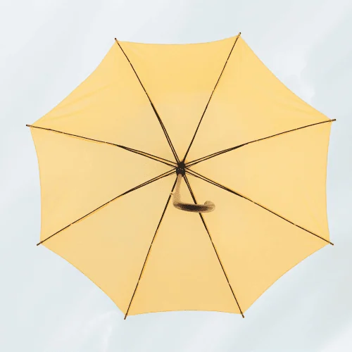 A low-angle view of a bright yellow umbrella against a pale sky, representing an integrated layer of AI for family office software.